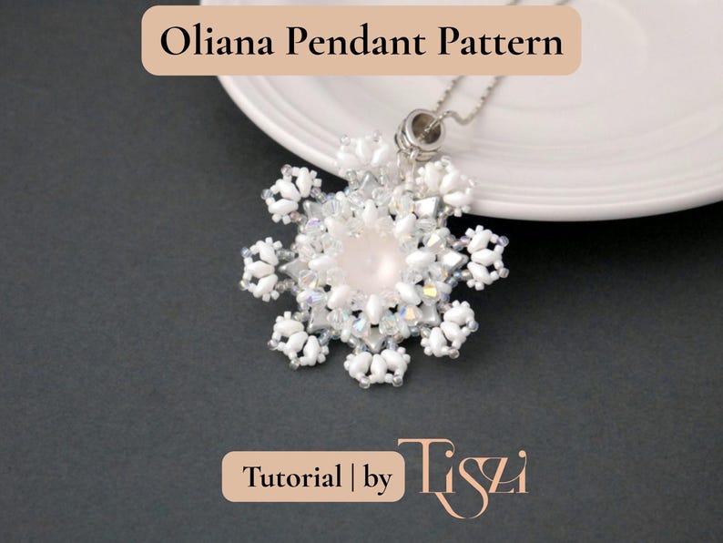 Puede incluir: Un collar con colgante de cuentas blancas con una piedra rosa central, que se asemeja a un copo de nieve. El colgante cuelga de una cadena plateada. El texto "Oliana Pendant Pattern" y "Tutorial by Tiszi" son visibles.