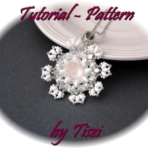 Può includere: Un ciondolo a forma di fiocco di neve bianco con un centro di perla, appeso a una catena d'argento. Il ciondolo è fatto di piccole perline bianche e cristalli trasparenti. Il ciondolo è su un piatto bianco con il testo "Tutorial - Pattern by Tizzi" sotto.