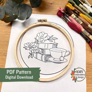 May include: A black and white line drawing of a stack of books with a cup of tea and flowers. The drawing is in a wooden embroidery hoop. The text "PDF Pattern Digital Download" is at the bottom of the image. The text "KMV Embroidery & Design" is at the bottom right of the image.