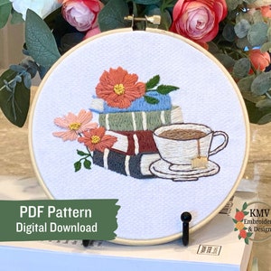 Könnte beinhalten: Stickerei in einem runden Rahmen mit einem Stapel Bücher, einer Tasse Tee und Blumen. Der Text "PDF Pattern Digital Download" befindet sich am unteren Rand des Bildes.