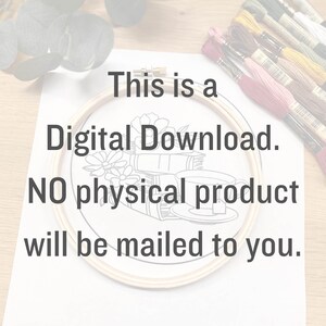 May include: A white sheet of paper with the text "This is a Digital Download. NO physical product will be mailed to you." printed on it. A wooden embroidery hoop with a black and white line drawing of a cup of tea and books is on the paper. A bundle of embroidery floss is on the right side of the paper.