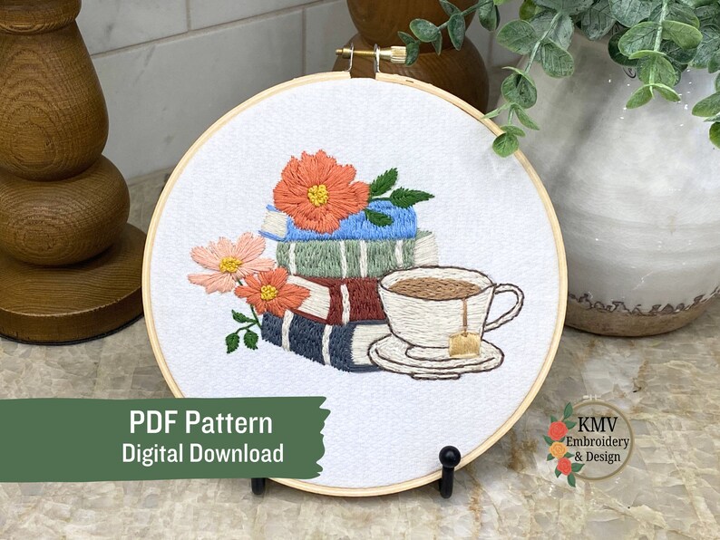 May include: Embroidered hoop art featuring a stack of books with flowers and a cup of tea. The design is in shades of blue, green, red, and brown. The text "PDF Pattern Digital Download" is at the bottom of the image.
