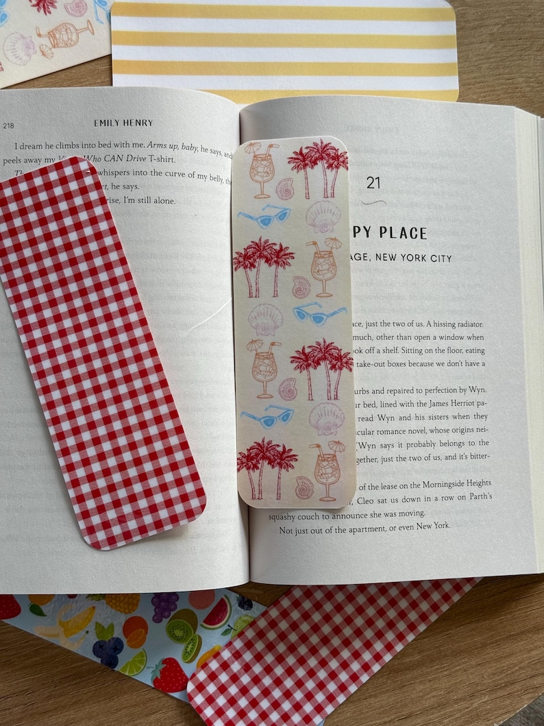 May include: A collection of bookmarks and decorative paper items. One bookmark features a red and white gingham pattern. Another bookmark has a cream background with illustrations of palm trees, cocktails, sunglasses, and seashells. Other paper items have fruit and striped patterns.