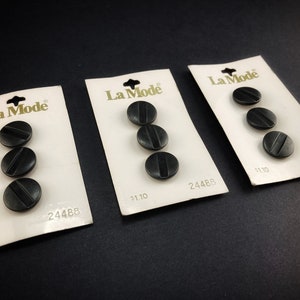 May include: Three cards of black buttons with a gold La Mode label and the number 24488. Each card has three buttons and the price $1.10 is printed on each card.