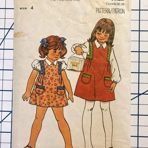 Puede incluir: Un patrón de costura vintage para un vestido de niña. El patrón es para la talla 4 y presenta dos ilustraciones de niñas que llevan el vestido. El vestido tiene un estampado floral y un bolsillo en la parte delantera. El patrón es de Butterick, the fashion one, y el número de patrón es 4929.