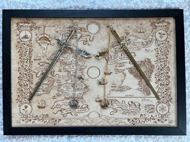 May include: Framed artwork showing a map with two decorative swords. The map is tan with dark brown details, depicting a fantasy world. The swords are silver and gold, with intricate designs. The frame is black.