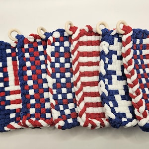 Puede incluir: Colecci&oacute;n de salvamanteles tejidos en rojo, blanco y azul, con aros de madera. Los dise&ntilde;os incluyen patrones de cuadros, rayas y colores lisos, evocando un tema patri&oacute;tico. Cada salvamanteles mide aproximadamente 20 cm de ancho.