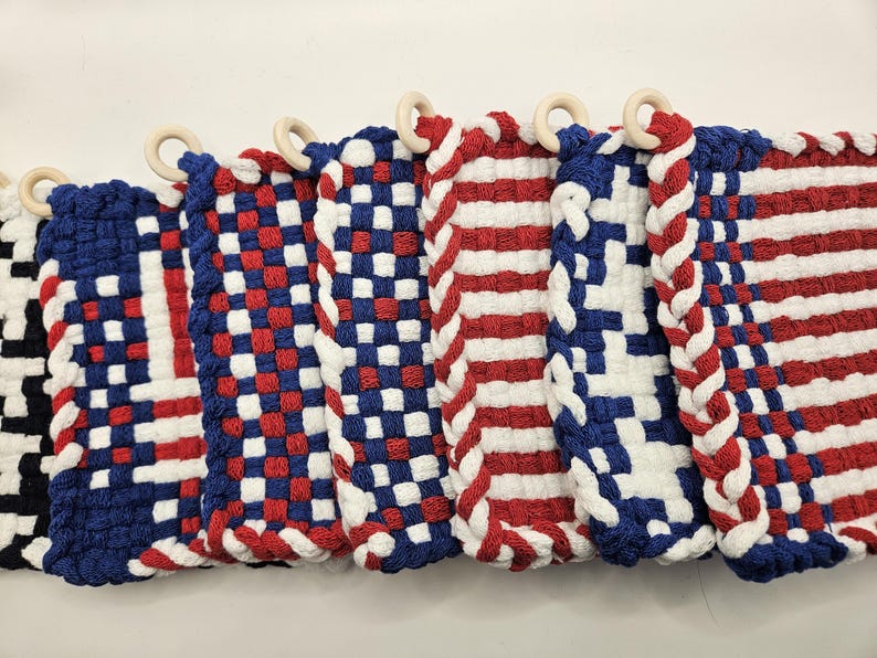 Puede incluir: Colecci&oacute;n de salvamanteles tejidos en rojo, blanco y azul, con aros de madera. Los dise&ntilde;os incluyen patrones de cuadros, rayas y colores lisos, evocando un tema patri&oacute;tico. Cada salvamanteles mide aproximadamente 20 cm de ancho.