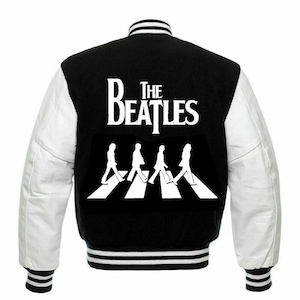 May include: Black and white varsity jacket with white leather sleeves. The back of the jacket features a white graphic of the Beatles walking across a crosswalk with the text "The Beatles".