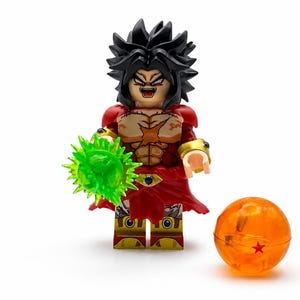 May include: A plastic minifigure with spiky black hair, a red and gold outfit, and a muscular torso design. The figure holds a translucent green energy blast accessory in one hand and stands next to a translucent orange sphere with a red star.