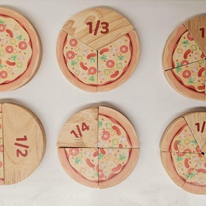 Puede incluir: Seis rebanadas de pizza de madera con diferentes fracciones impresas en ellas. Las fracciones son 1/2, 1/3, 1/4, 1/5 y 1/6. Cada rebanada tiene un diseño de cobertura de pizza.