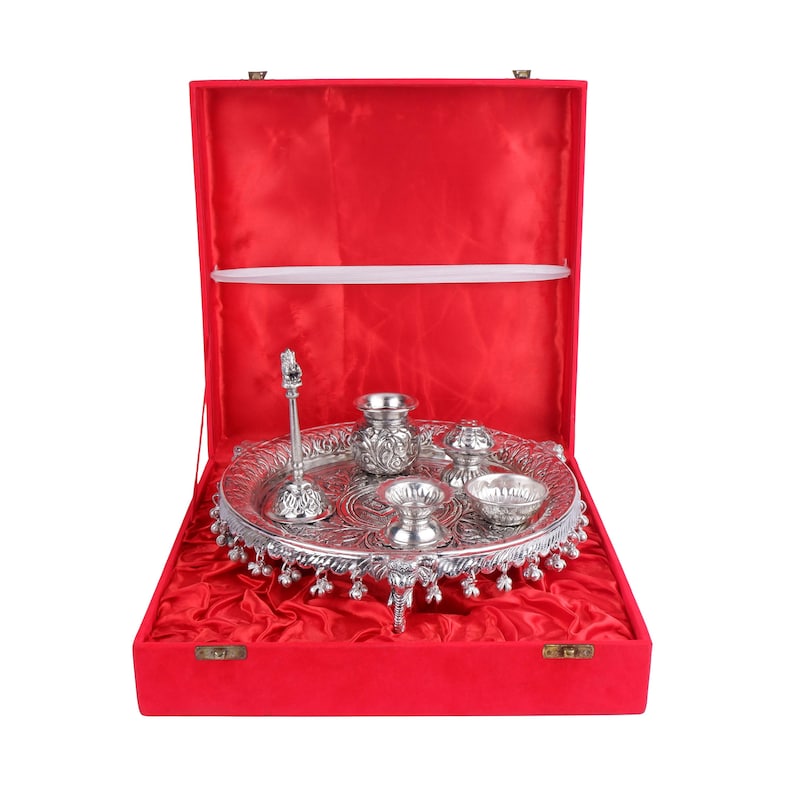 Puede incluir: Un juego religioso plateado, que incluye una bandeja, cuencos peque&ntilde;os y un soporte decorativo, presentado en una caja forrada de terciopelo rojo. El juego presenta patrones y dise&ntilde;os intrincados, ideal para ceremonias religiosas.