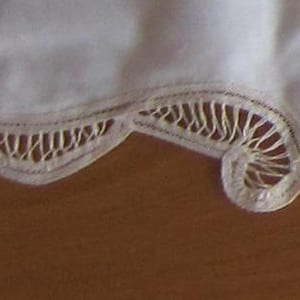 Peut inclure: Un chemin de table en dentelle blanche avec un motif floral délicat. Le chemin de table est fait d'un tissu fin et léger et a un bord festonné.