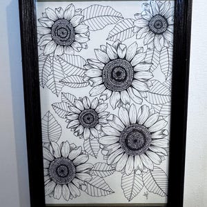 May include: Black framed artwork featuring a detailed pen and ink drawing of sunflowers and leaves. The sunflowers are in various stages of bloom, with intricate petal and seed head details. The leaves are also meticulously drawn, creating a botanical theme.