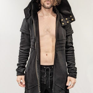 May include: A black hooded long-sleeved jacket with a zip closure and gold-coloured snaps. The jacket has a long, flowing design and is made of a soft, comfortable fabric.