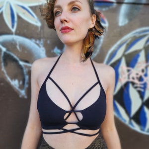 Puede incluir: Un top negro de halter con tirantes cruzados y un diseño de corte. El top está hecho de una tela suave y elástica y tiene un ajuste cómodo.