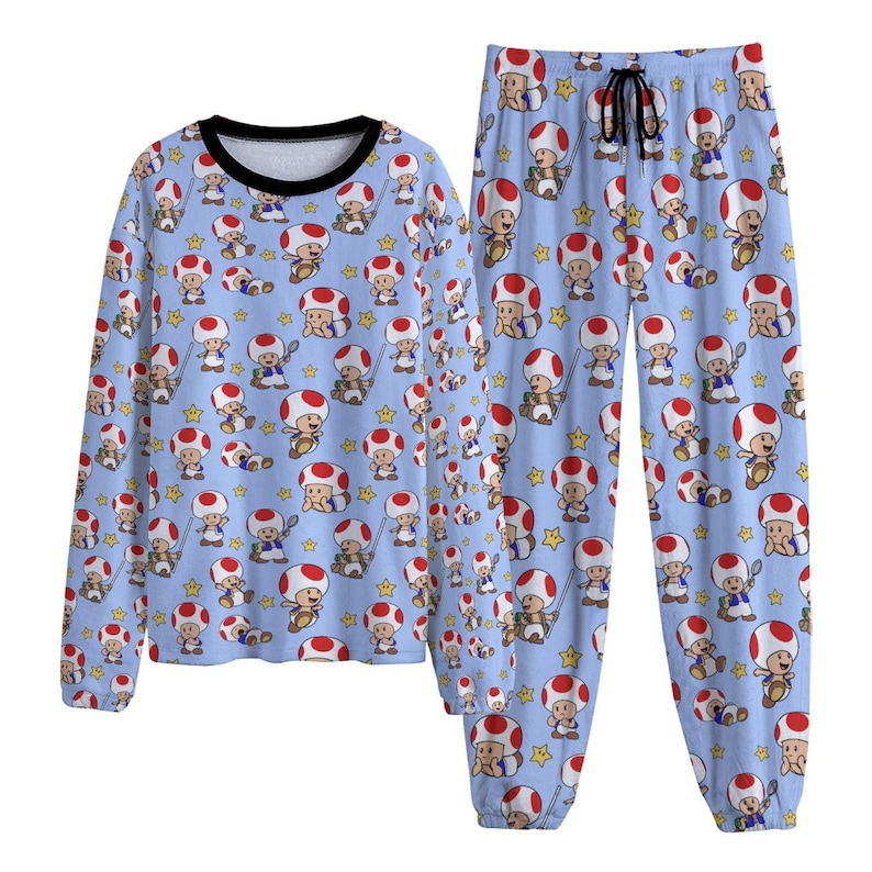 May include: A light blue pajama set featuring a repeating pattern of the character Toad from the Super Mario video game series. The long-sleeved top has a black collar, and the pants have a drawstring waist. The design includes Toad, stars, and mushrooms.