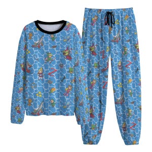 Pode incluir: Um conjunto de pijama azul com um padrão repetido de personagens e símbolos de videojogos. A parte superior de manga comprida tem uma gola preta e as calças têm uma cintura com cordão. O design inclui espadas, personagens e a letra "Z".