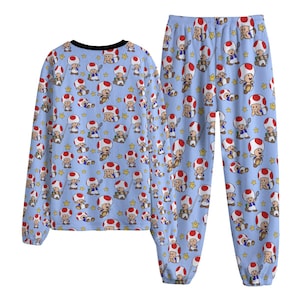 May include: A light blue pajama set featuring a repeating pattern of cartoon mushroom characters with red and white caps. The long-sleeved top has a black collar, and the pants have an elastic waistband. The pajamas are made of a soft, comfortable material.