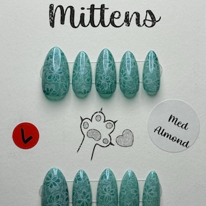 May include: A set of teal almond-shaped press-on nails with a white floral lace design. The words "Murder Mittens" are at the top. The size is "Med Almond". The bottom of the card has the text "CirqueColors-Elixir of Everlasting Life".