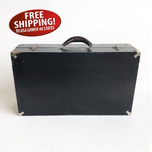 May include: A black vintage suitcase with a leather handle and silver accents. The suitcase is closed and has a smooth surface.