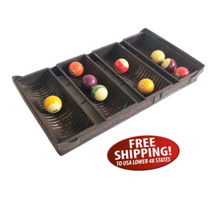 May include: A vintage metal rack with six slots for holding billiard balls. The rack is rusty and has a corrugated surface. The balls are various colors, including red, yellow, and white.