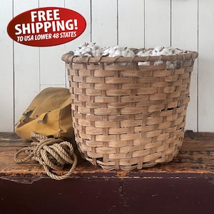 May include: A large, woven basket filled with cotton bolls. The basket is light brown and sits on a wooden surface. A tan bag and rope are next to the basket. The image includes a red oval with the text "FREE SHIPPING! TO USA LOWER 48 STATES".