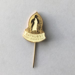 May include: Gold-colored pin with a white penguin and the text "Bathurst Rugby Leagues Club".