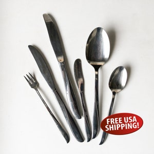 May include: Set of five silver-toned flatware pieces, including a fork, two knives, a butter knife, and a spoon. Each piece has a star design.