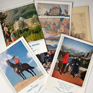 May include: A vintage postcard featuring a view of the Banff Springs Hotel in the Canadian Rockies. The postcard shows the hotel in the distance with mountains in the background. The text on the postcard reads "Bow Valley from the Terrace Banff Springs Hotel Canadian Rockies".