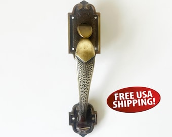 May include: Ornate bronze door handle with a textured grip and decorative backplate. The handle features a unique design with a curved top and a detailed, patterned grip, ideal for vintage or antique doors.