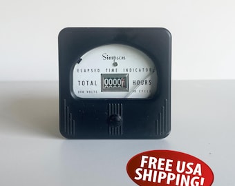 May include: A black Simpson elapsed time indicator with a white face and the text "ELAPSED TIME INDICATOR". The indicator shows "0000" hours. The device is square with rounded corners and a small button.