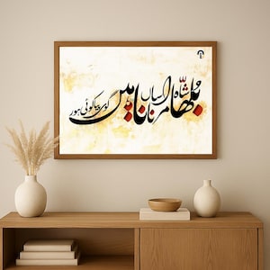 以下が含まれることがあります： クリーム色の背景に、黒と赤のエレガントなウルドゥー語カリグラフィーが施された額入りのアートワーク。木製のフレームが作品の暖色を補完しています。木製のキャビネットの上に、装飾的な花瓶と一緒に展示されています。