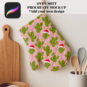May include: Pink oven mitt with a repeating pattern of green cacti wearing Santa hats and candy canes. The text "OVEN MITT PROCREATE MOCK UP *Add your own design" is at the top. The mitt is hanging on a white wall.