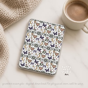 Puede incluir: Una funda transparente con un patr&oacute;n repetido de mariposas, corazones, llaves, lunas, estrellas y lazos en morado, rosa, dorado y blanco. La funda est&aacute; sobre una superficie blanca junto a una taza de caf&eacute; y un art&iacute;culo de punto beige. El texto "Sunny Nest Studio Art" es visible.