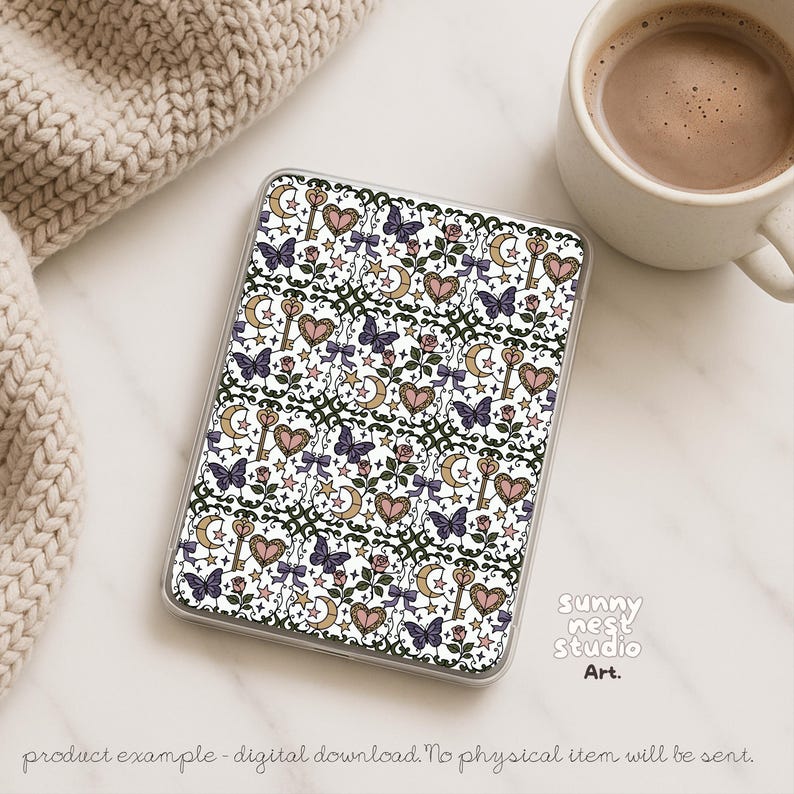 Puede incluir: Una funda transparente con un patr&oacute;n repetido de mariposas, corazones, llaves, lunas, estrellas y lazos en morado, rosa, dorado y blanco. La funda est&aacute; sobre una superficie blanca junto a una taza de caf&eacute; y un art&iacute;culo de punto beige. El texto "Sunny Nest Studio Art" es visible.