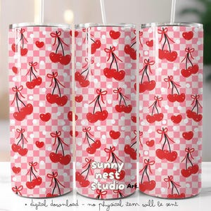 May include: A set of three stainless steel tumblers with a repeating pattern of red cherries and hearts on a pink and white checkered background. The tumblers have a silver straw and the text "sunny nest studio art" is visible.
