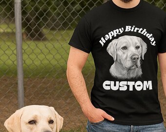 Może przedstawiać: Czarny t-shirt z portretem labradora i białymi napisami "Happy Birthday" i "CUSTOM". Osoba nosząca koszulkę stoi obok żółtego psa rasy labrador. Tło obejmuje ogrodzenie z siatki drucianej i zielone liście.