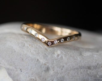 May include: A gold band ring with a V-shaped design and small diamonds set along the edge.
