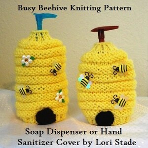 May include: Knitted beehive-shaped soap dispenser or hand sanitizer cover in yellow with black and white bee embellishments and white flowers. The pattern is called "Busy Beehive Knitting Pattern" and is by Lori Stade.