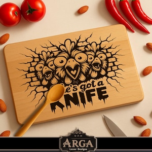 Könnte beinhalten: Rechteckiges Holzschneidebrett mit humorvollem Design. Das Brett zeigt eine schwarze Grafik von drei Cartoon-Hühnern, die durch eine Ziegelmauer brechen, mit dem Text "e's got a KNIFE". Ein Holzlöffel und ein Messer sind ebenfalls vorhanden.
