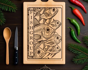Może przedstawiać: Drewniana deska do krojenia z uchwytem, ​​wygrawerowana wzorem ryby i napisem "FISH GROUP". Deska otoczona jest czerwonymi i zielonymi papryczkami chili, drewnianą łyżką i nożem. Logo "ARGA Laser Designs" znajduje się na dole.