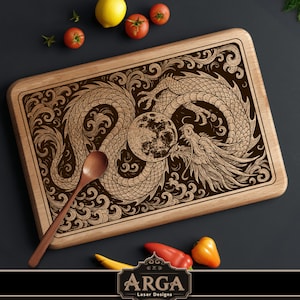 May include: Wooden cutting board with a detailed dragon and moon design. The dragon is intricately carved, with a moon in the center. A wooden spoon rests on the board. The board is surrounded by fresh vegetables.