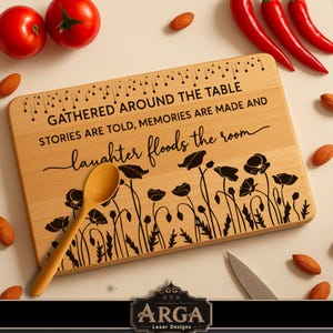 May include: A wooden cutting board with the text "GATHERED AROUND THE TABLE STORIES ARE TOLD, MEMORIES ARE MADE AND laughter floods the room" and a floral design. A wooden spoon and a knife are on the board. Red tomatoes, chili peppers, and almonds surround the board.