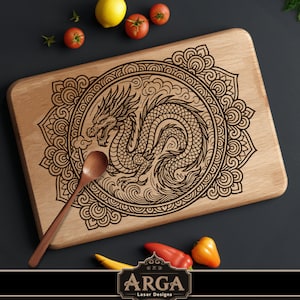 May include: Wooden cutting board with a laser-etched dragon design. The dragon is centered within a circular pattern. A wooden spoon rests on the board. The board is surrounded by tomatoes, a lemon, and peppers. The logo "ARGA Laser Designs" is at the bottom.