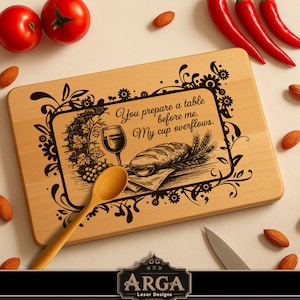 May include: Wooden cutting board with engraved text and illustrations. The text reads "You prepare a table before me. My cup overflows." Includes a wooden spoon, tomatoes, almonds, and red peppers.