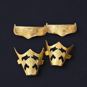 May include: Two curved, gold-colored metal headbands featuring intricate floral engravings and two matching gold-colored metal crown-like pieces with openwork geometric patterns and detailed etched textures on the surface of the metal.