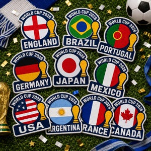 May include: A collection of embroidered patches featuring flags of various countries participating in the World Cup 2026. Each patch includes the country's name and the text "World Cup 2026". The patches are on a green surface.