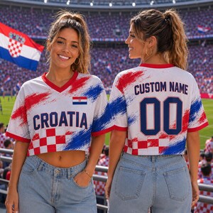 A woman wearing a red, white, and blue Croatia soccer jersey with the custom name "00" on the back, standing in front of a stadium filled with spectators.