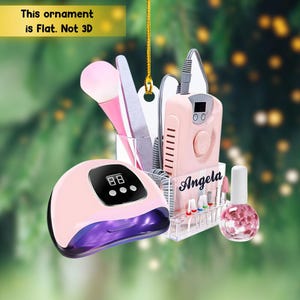 May include: A pink nail art ornament featuring a UV LED lamp, nail drill, nail polish, and various manicure tools. The ornament includes the text "This ornament is Flat. Not 3D" and the name "Angela".